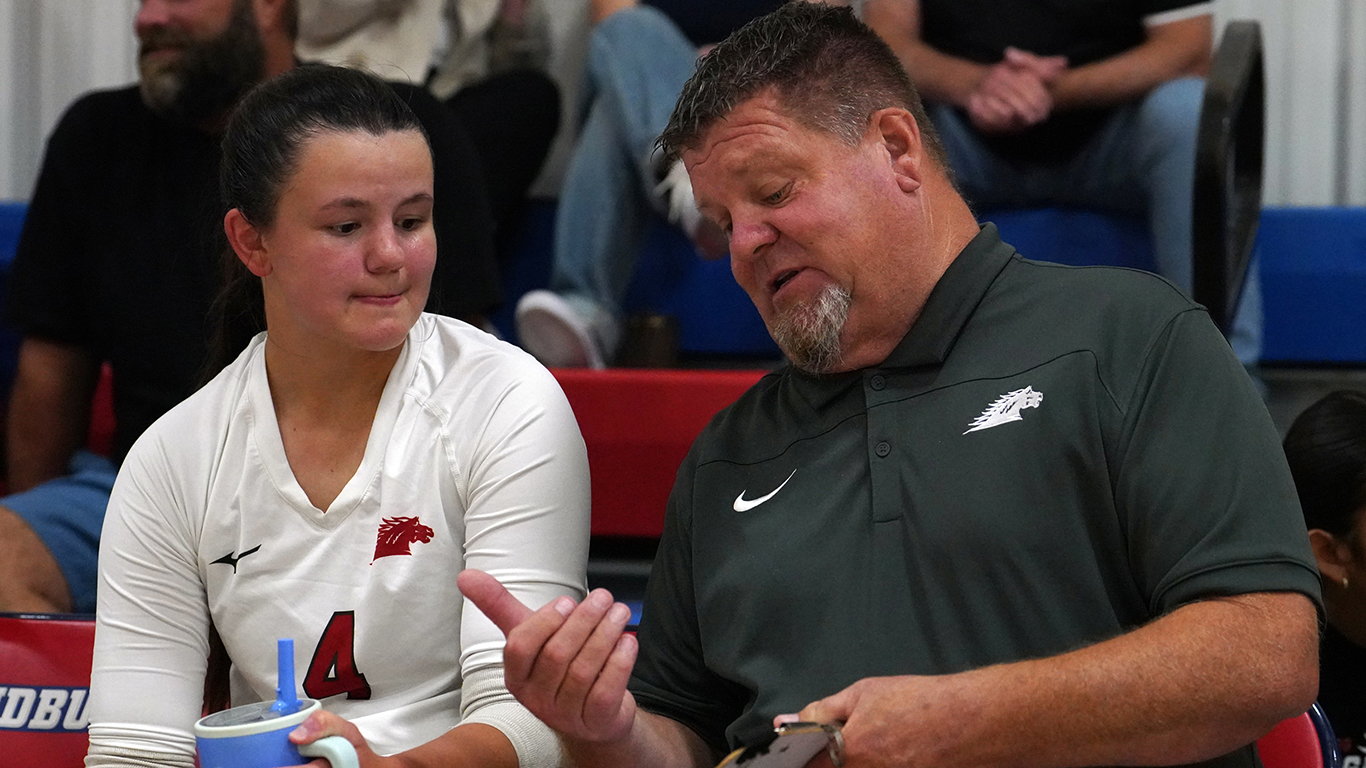 Sandburg volleyball player on bench talking with Todd Winkler.