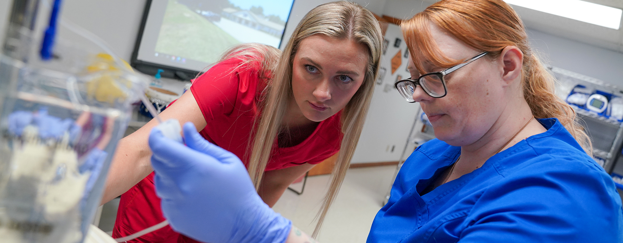 nursing instructor showing a student how to setup a an IV.