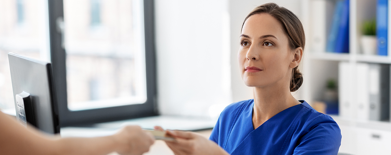Receptionist taking card from patient.