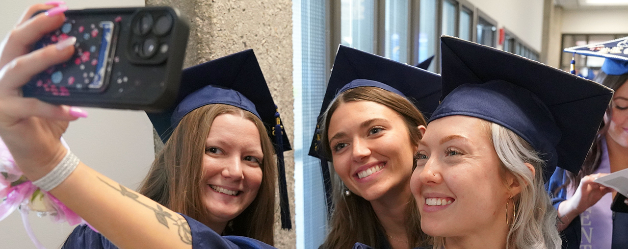 Three women at graduation taking a selfie.