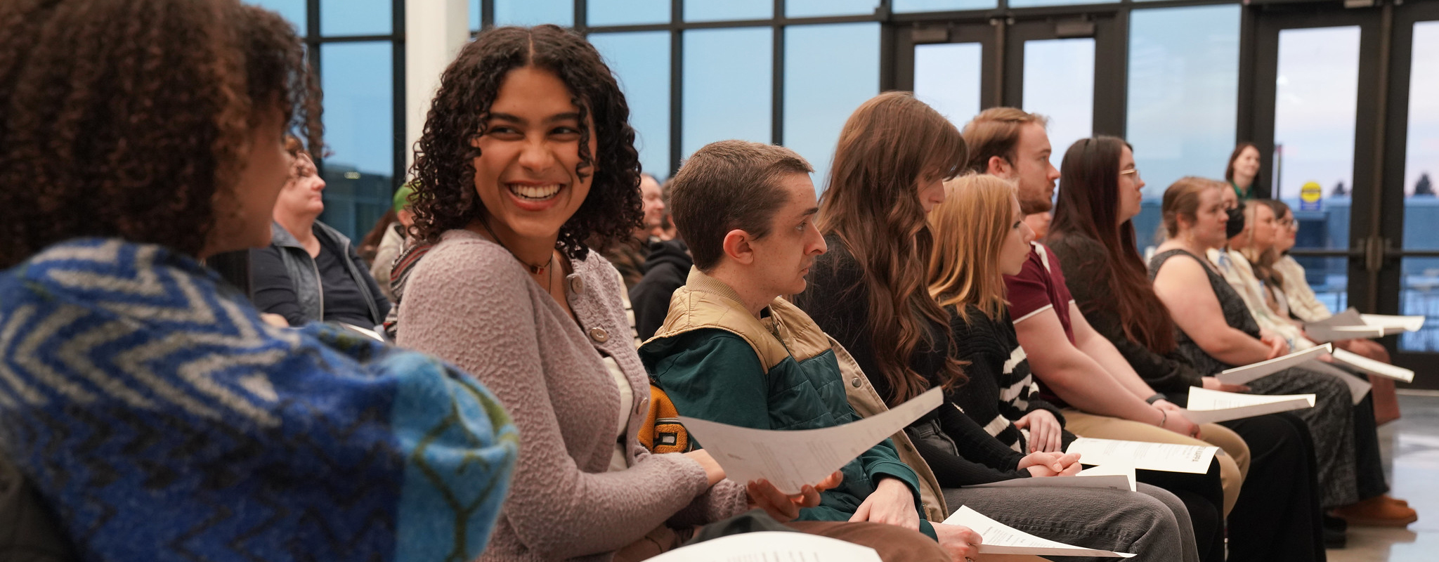 a row of students sitting in chairs smiling.