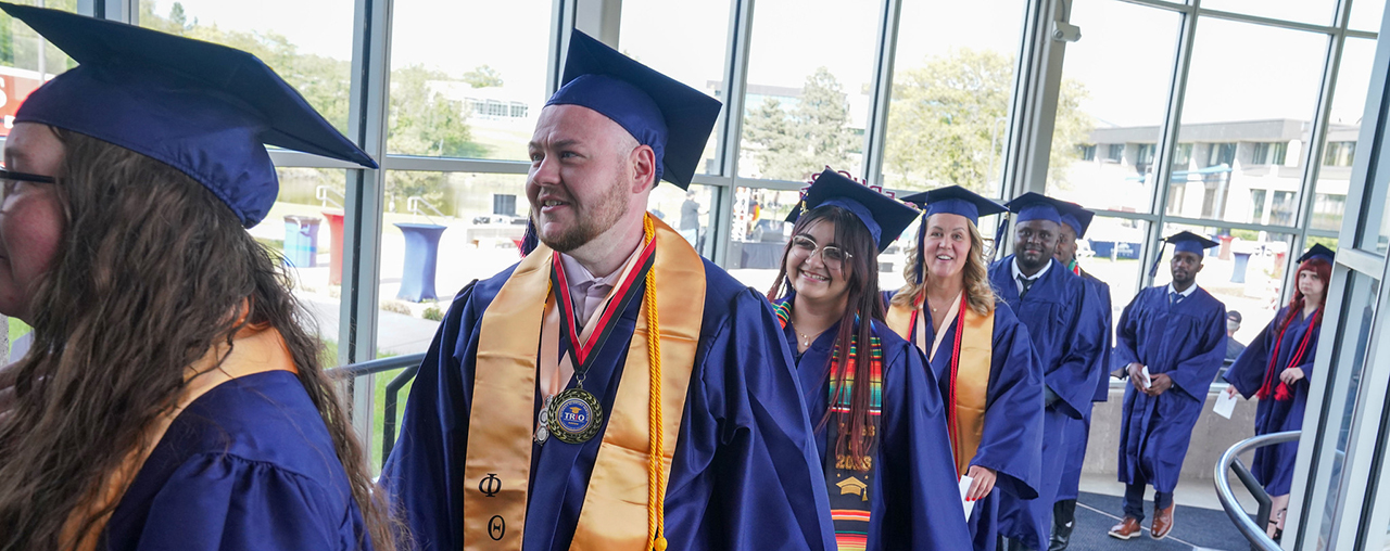 A line of students with their cap and gowns on for graduation ceremony.