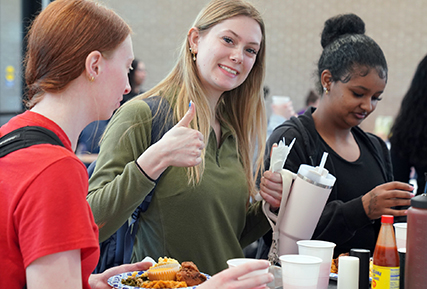 Three female students getting food from food tasting day.
