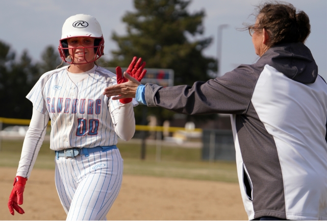 Softball player high fiving a coach.