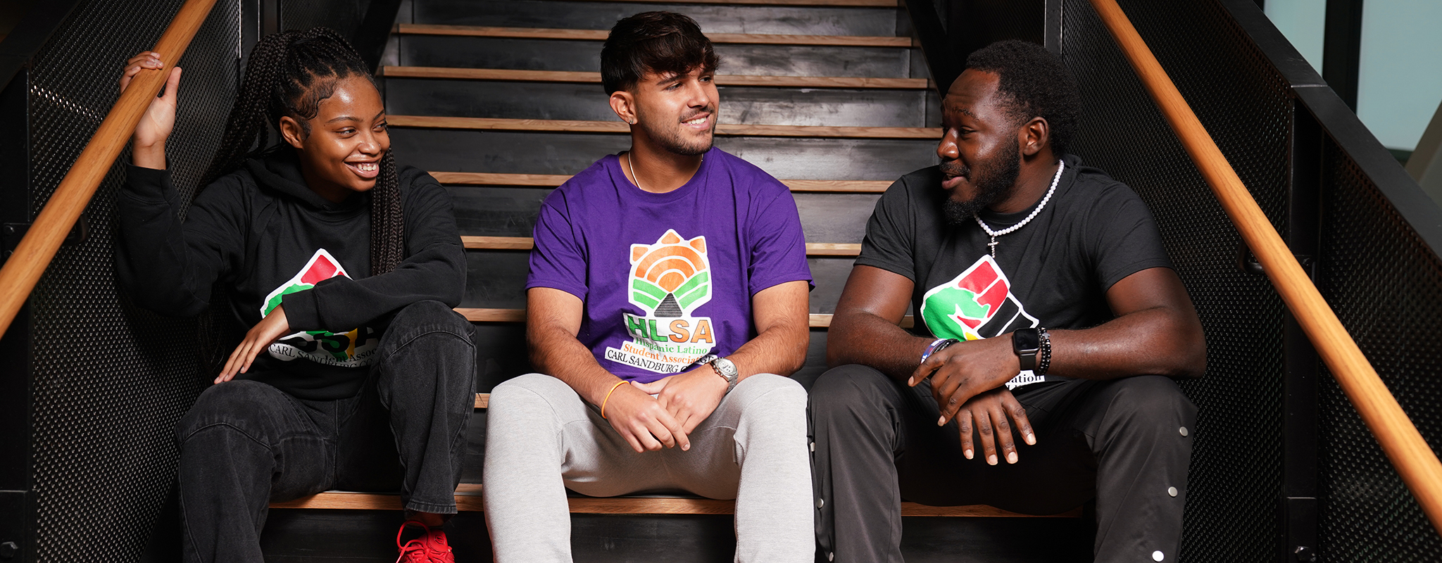 Three students sitting on stairs in the S&T building.