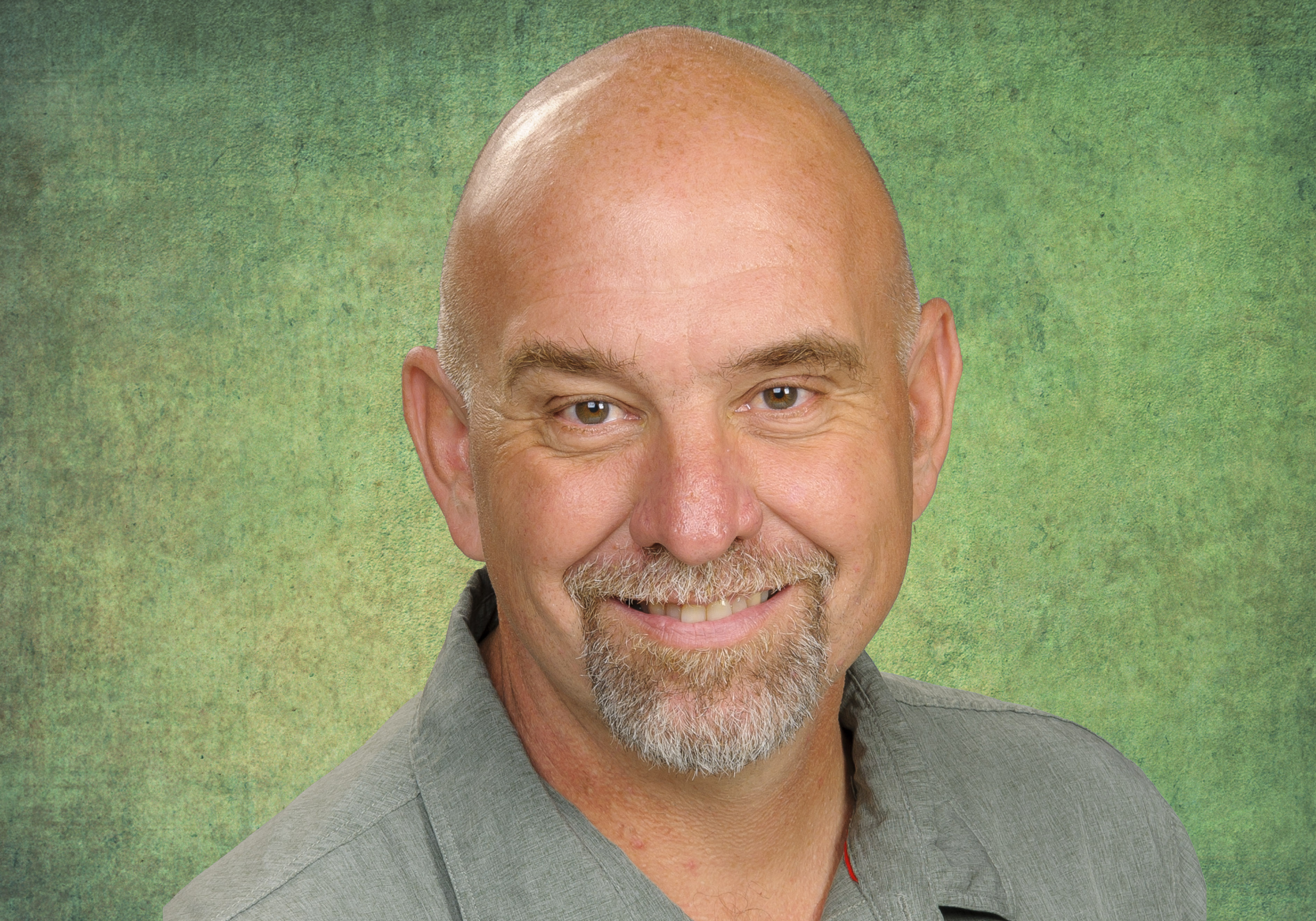 A bald man with facial hear smiling.