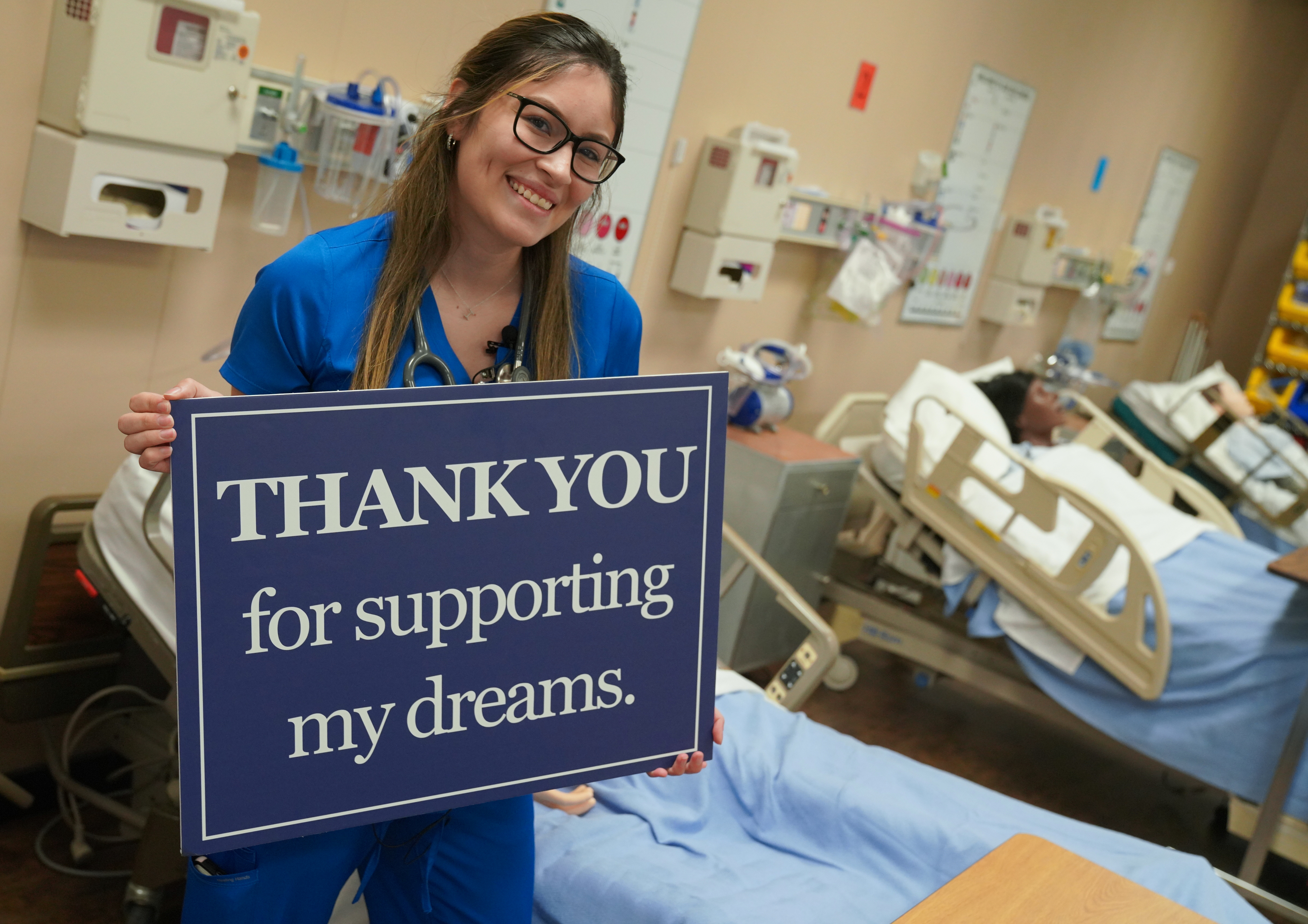 Nursing student holding a sign saying thank you for supporting my dreams.