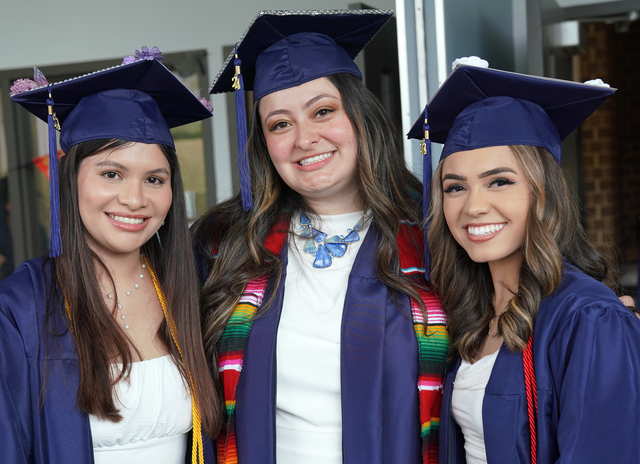 three women at graduation in cap and gown.