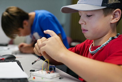 young boy looking at a circuit board. 