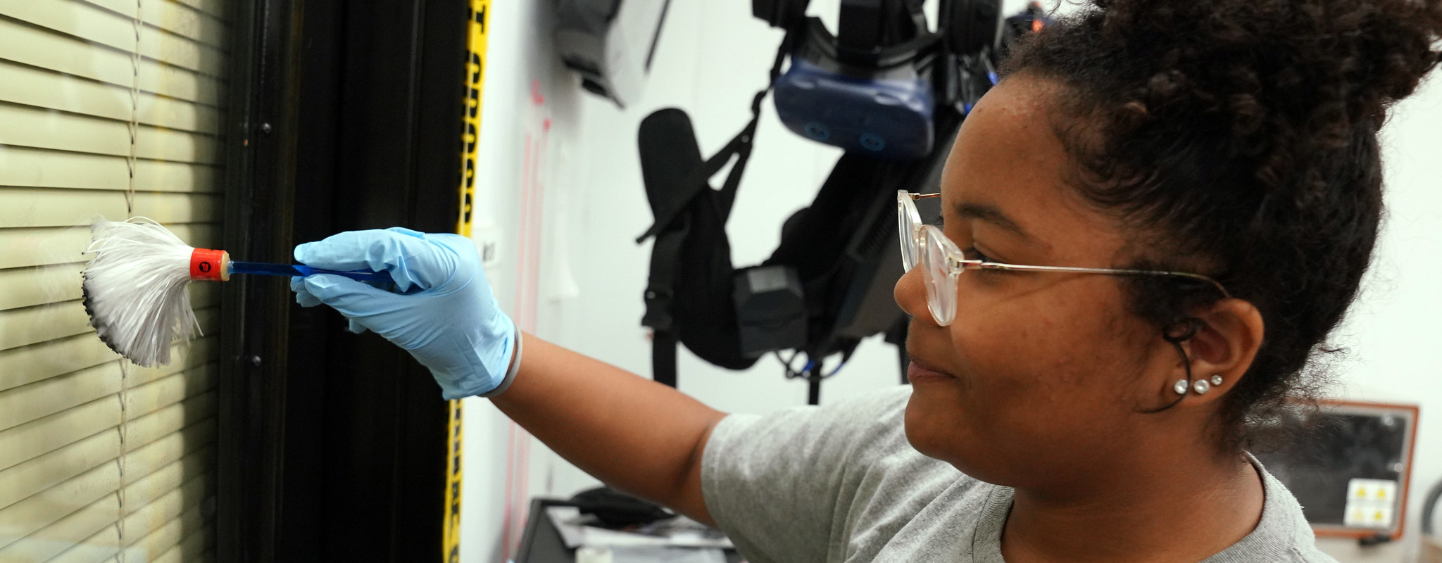 Student dusting for finger prints on a glass door.