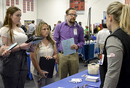 Three students talking to a college recruiter.