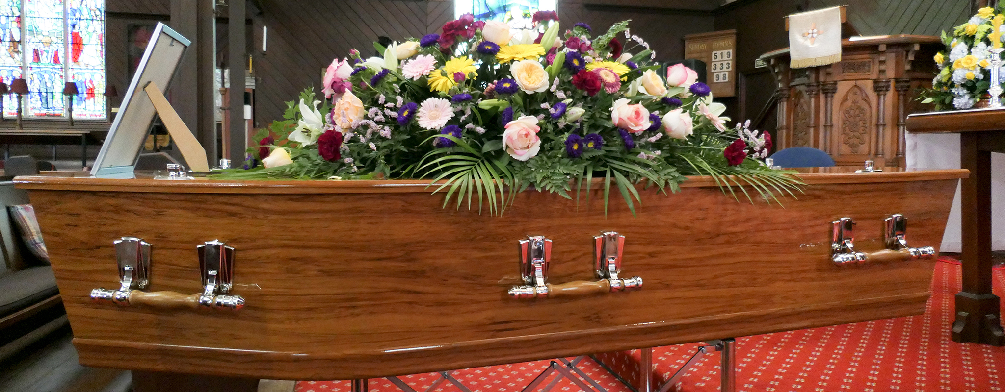 a caskit with flowers on top if it in a church.