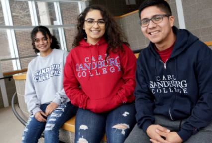 Three Sandburg students sitting in building C on a half wall