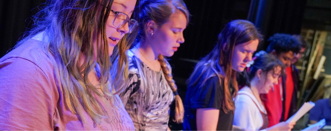 Students reading lines on a stage.