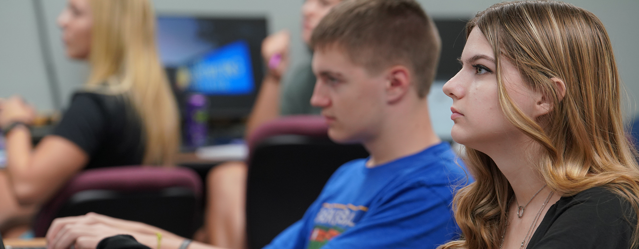 two students sitting in a classroom looking to the left.