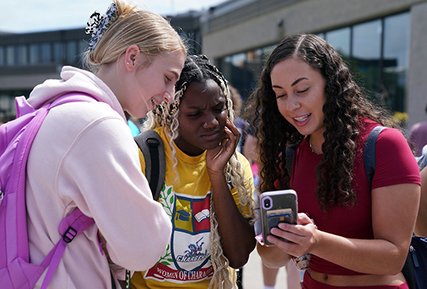 three women looking at a phone.