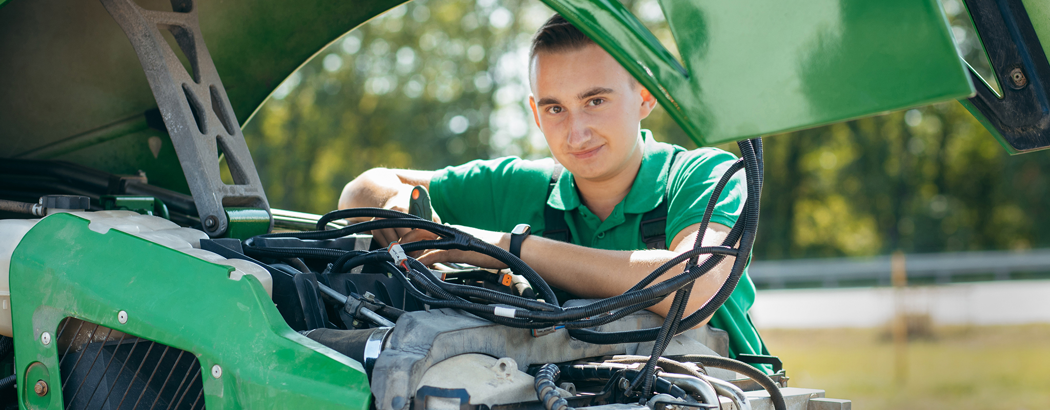 man standing behind a tractor with the hood up.