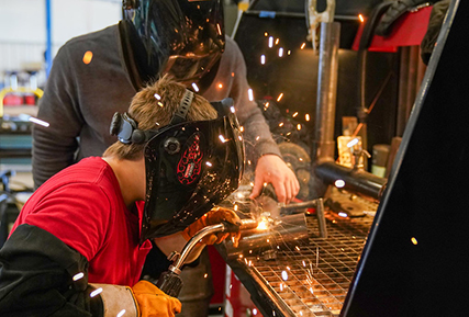 young man welding with an instructor in a welding lab.