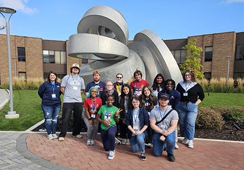 Students at conference standing near sculpture
