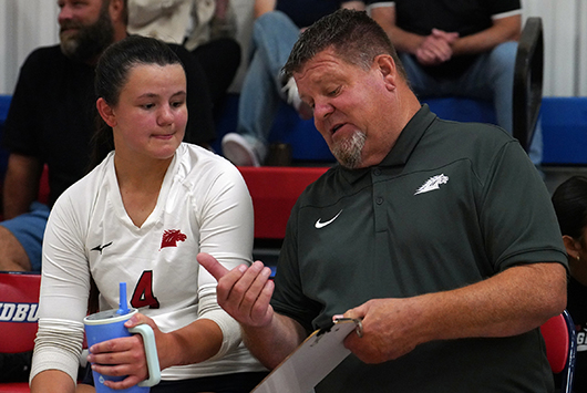Sandburg volleyball player talking on bench with coach Todd Winkler.