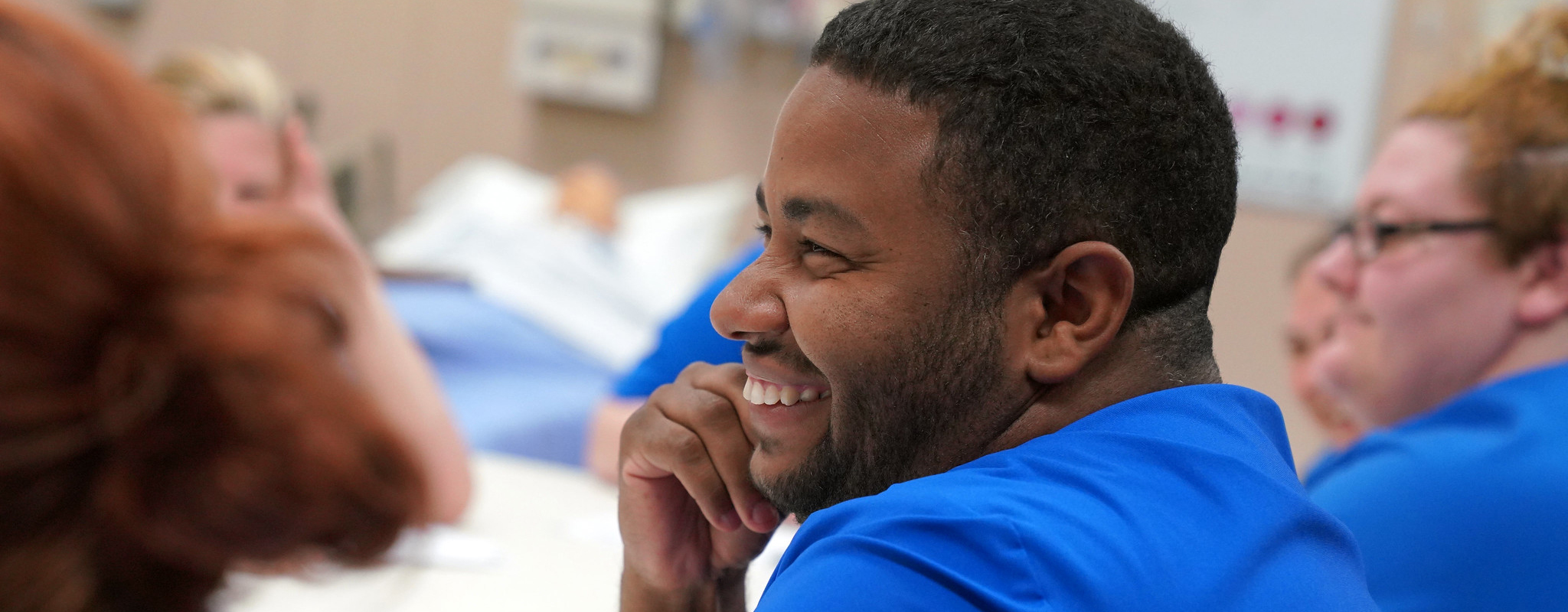 person smiling sitting in a nursing classroom.