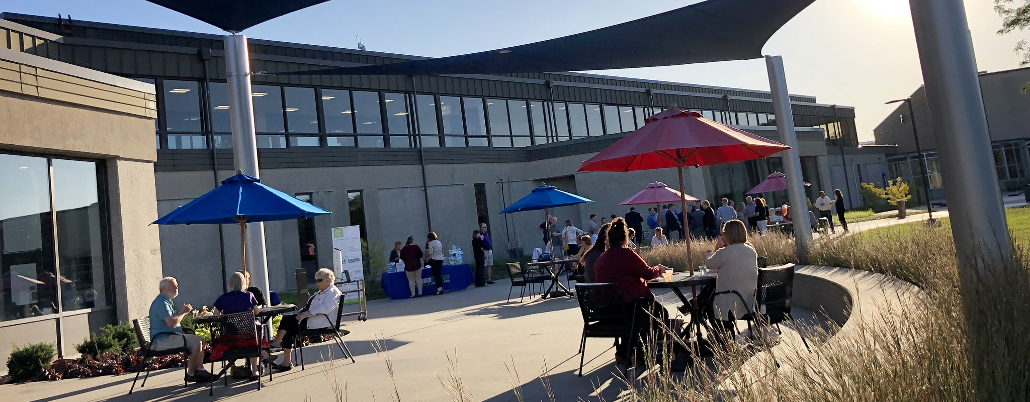 View of back patio on campus with people sitting at tables and chairs.