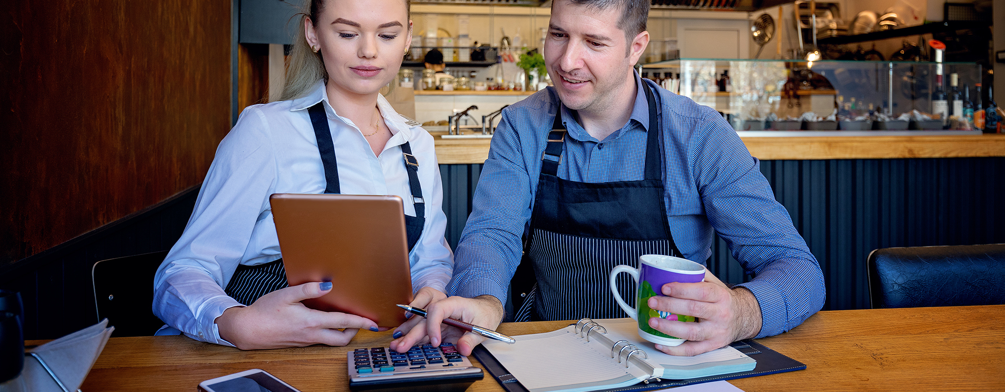 two people looking at an ipad at a desk working ona budget.