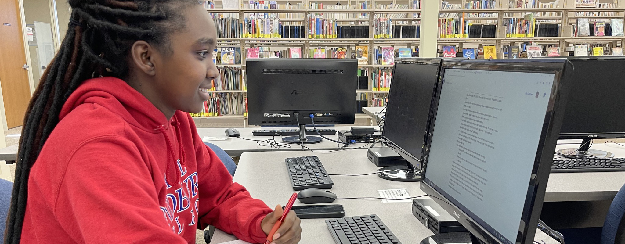 female student in library looking at computer screen.