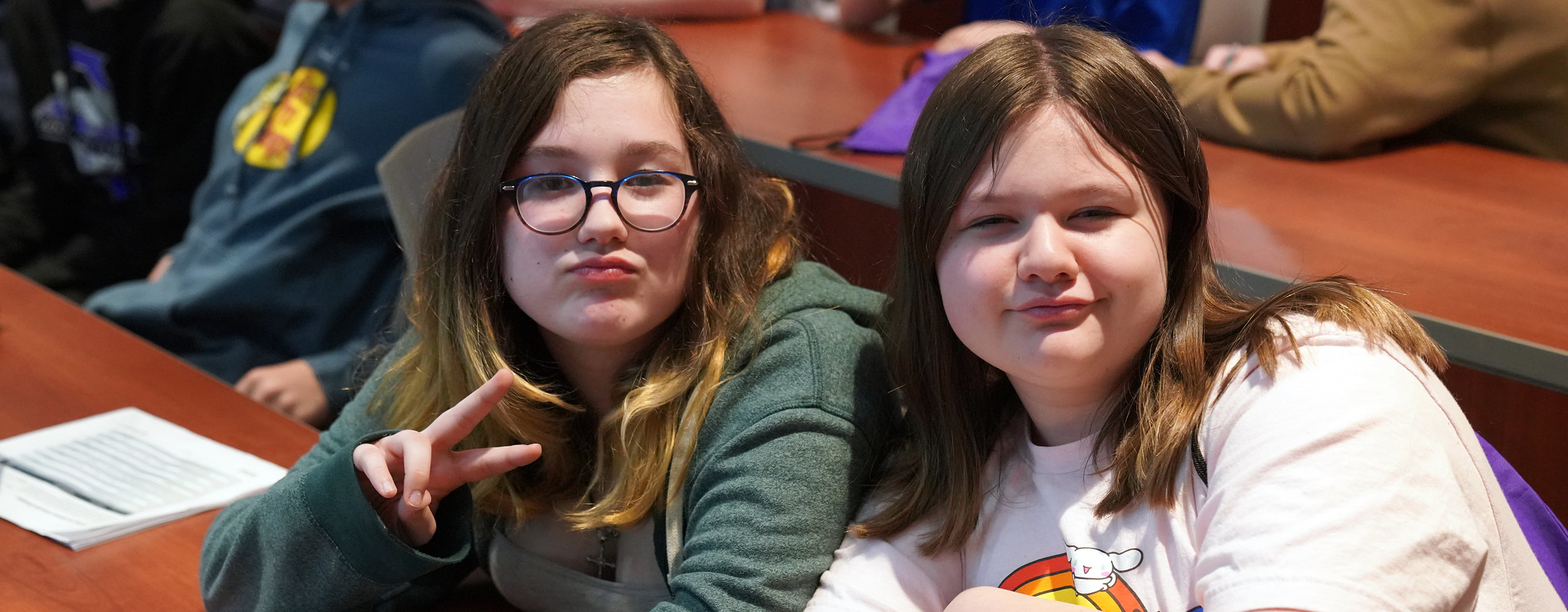 two students smiling sitting in a classroom.