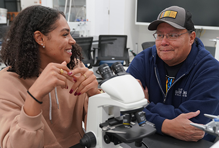 student and instructor in a biology lab talking.