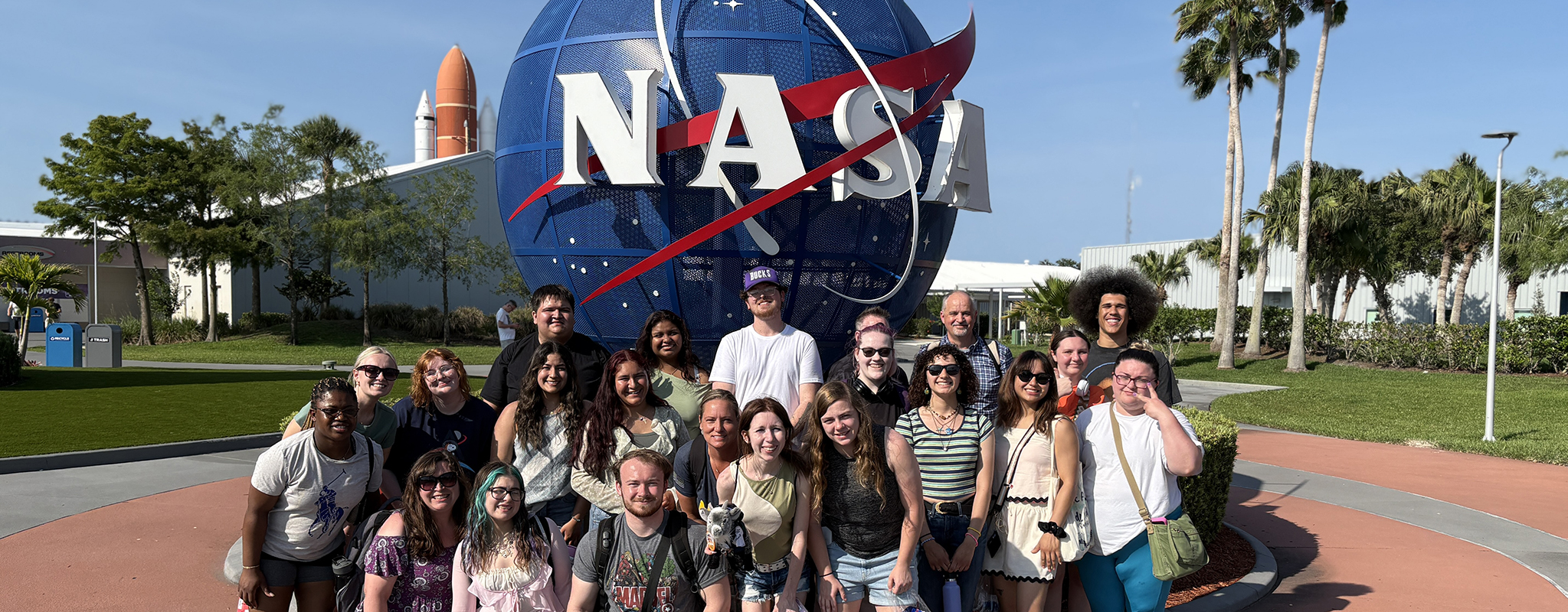 group of students standing in front of a large globe with the the letters NASA on it.