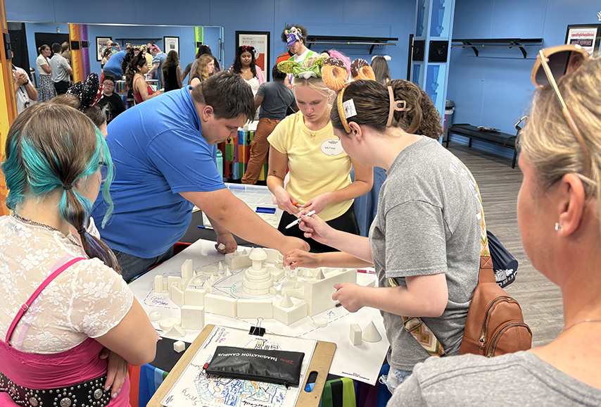 group of students standing around a table with a model of a castle.