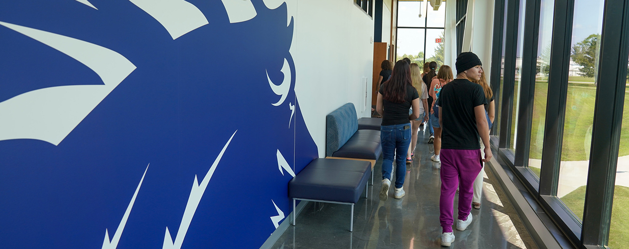A hallway with students walking down, with a drawing of a horse on the wall. 