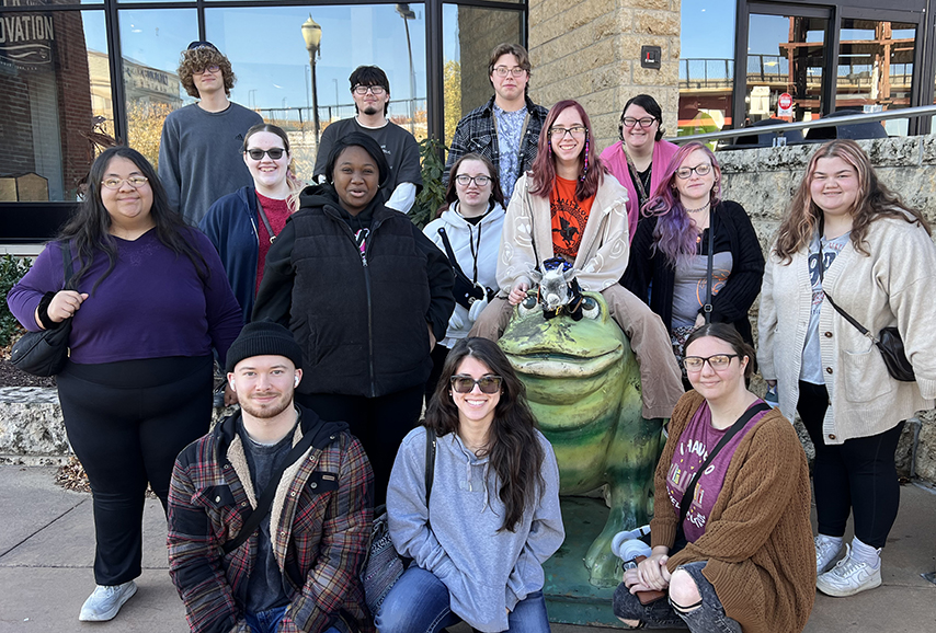 Group of students standing around a frog statue.